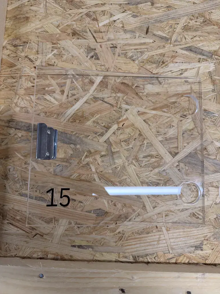 Transparente Fachabdeckung aus Acrylglas mit der Nummer 15 und Metallhalterung auf einer OSB-Platte