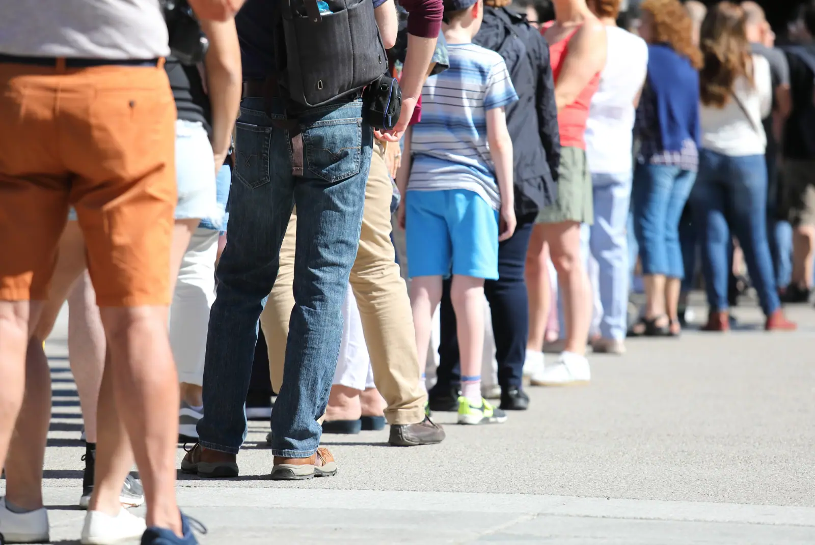 Viele Menschen stehen in einer langen Warteschlange geduldig hintereinander an