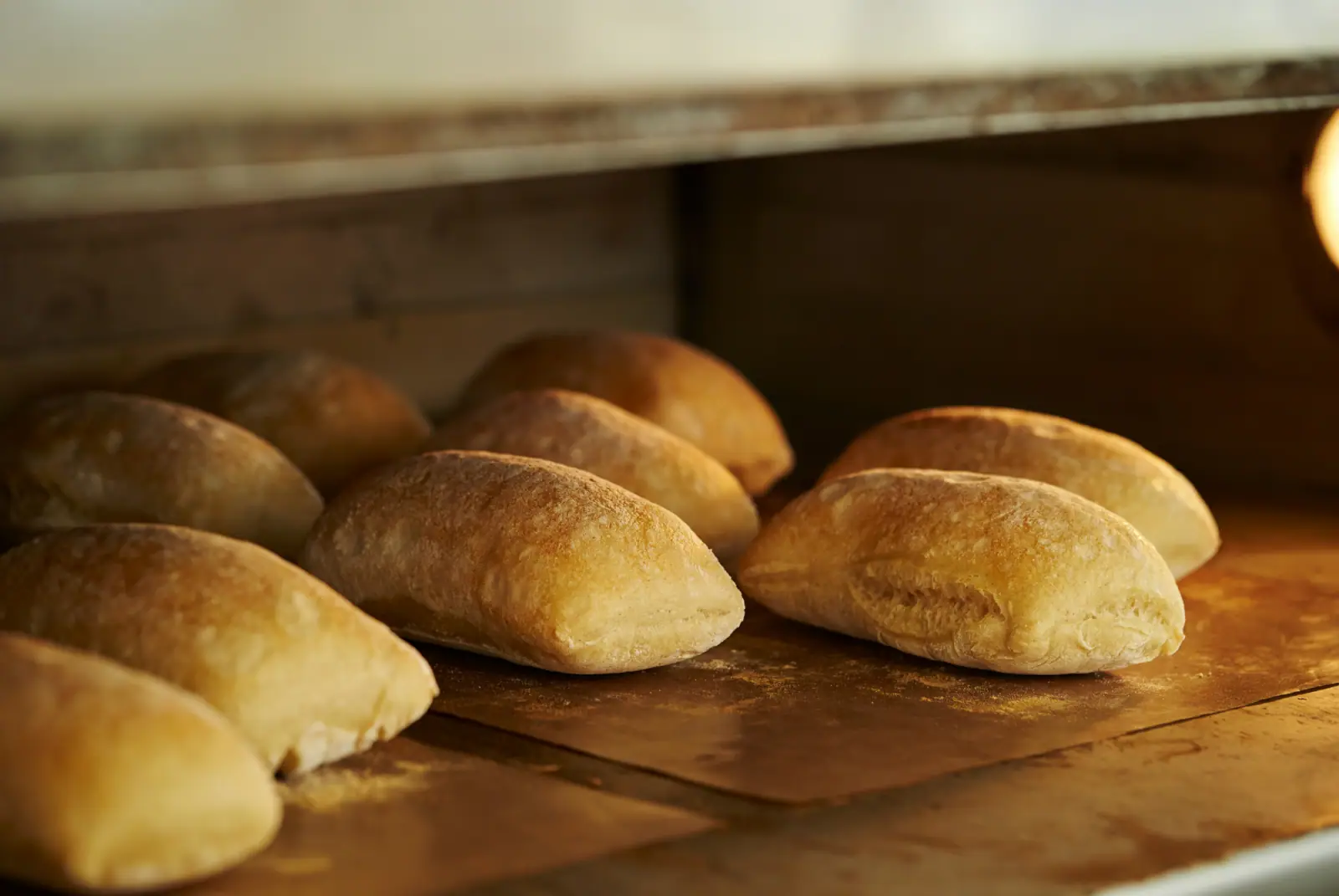 Goldbraun gebackene, rustikale Brötchen in einem warm beleuchteten Backofen