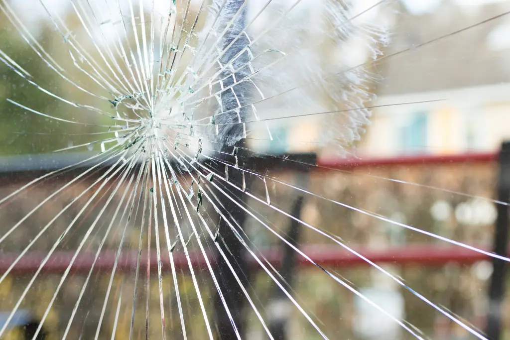 Gebroken glasplaat met een centraal inslagpunt en stervormig uiteenlopende barsten