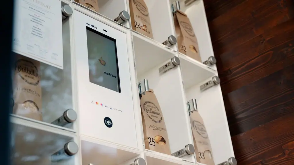 Digitale marktbox mit Touchscreen und Fächern voller Backwaren in Papiertüten vor einer Holzwand