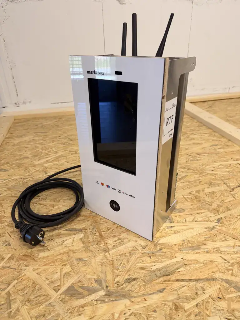 Marktbox-Modul mit Display, Bezahlfunktion und WLAN-Antennen auf einer Holzplatte