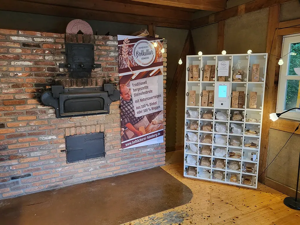 Moderne marktbox neben traditionellem Steinofen mit Backwaren in einer rustikalen Hofbäckerei