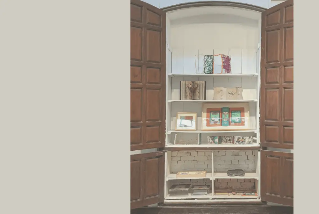 Geöffneter dunkler Holzschrank mit weißen Regalen, auf denen kleine Kunstgegenstände und Bücher ausgestellt sind