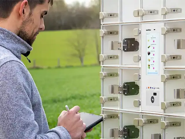 Mann verwaltet eine marktbox Verkaufsstation mit Touchscreen und Fächern über ein Tablet im Freien