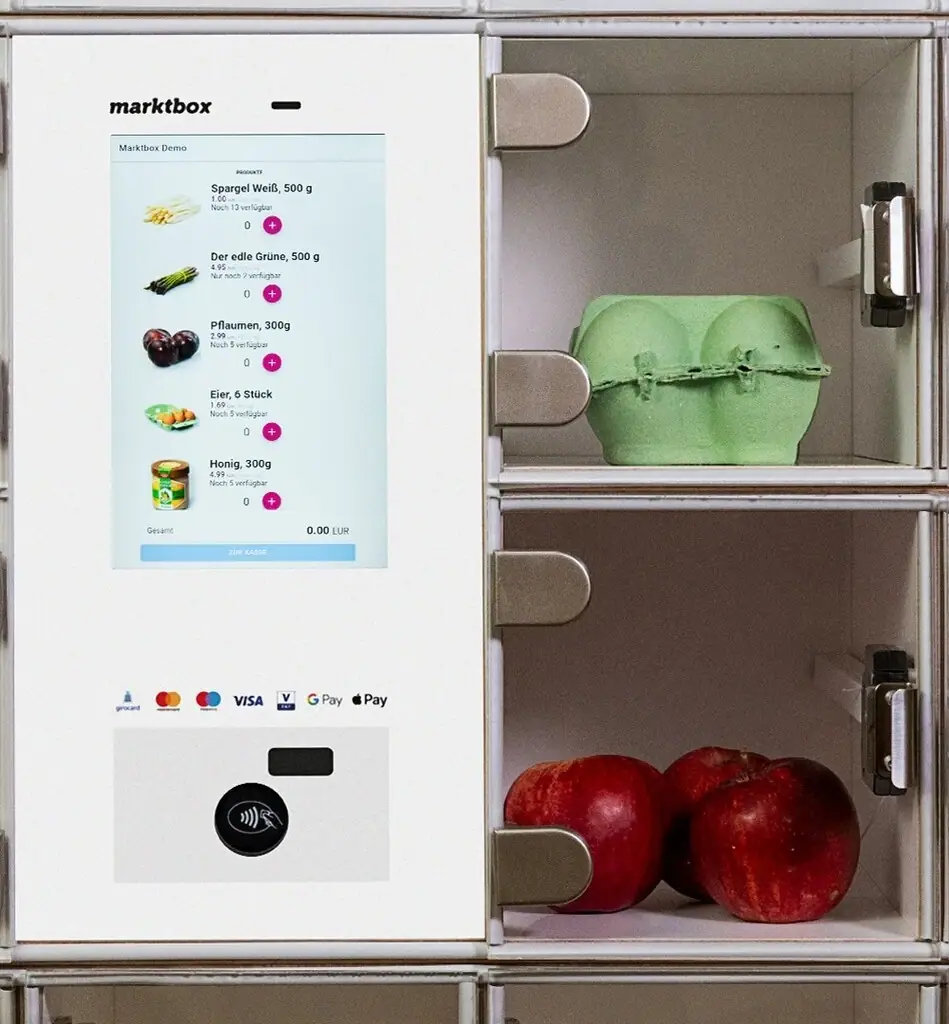 Digitale marktbox mit Touchscreen-Menü und Fächern, die einen Eierkarton sowie rote Äpfel enthalten