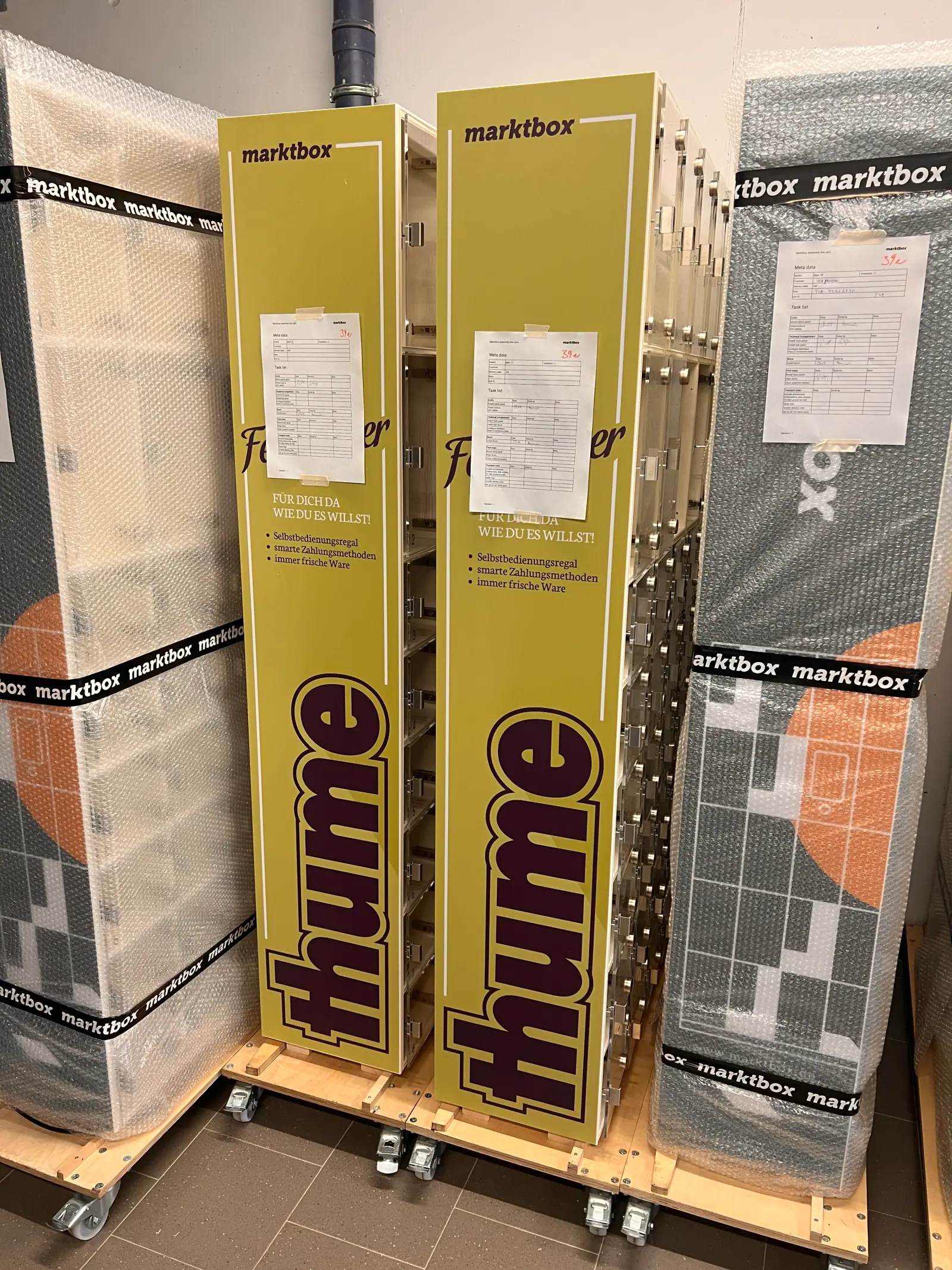 Marktbox-Automaten im thume-Design stehen fertig montiert und teils verpackt in einer Produktionshalle