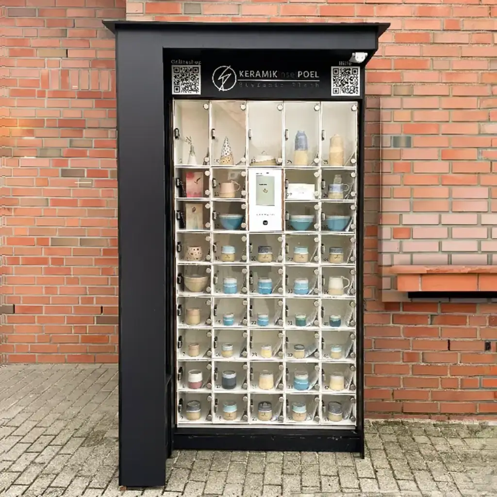 Eine schwarze marktbox mit Keramik in beleuchteten Glasfächern vor einer Ziegelwand