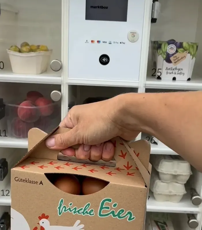 Kundin nimmt eine Eierbox aus einem Fach der marktbox